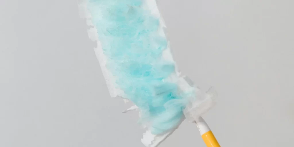 Duster de limpieza con cabezal azul y mango amarillo, ideal para eliminar el polvo de superficies delicadas.